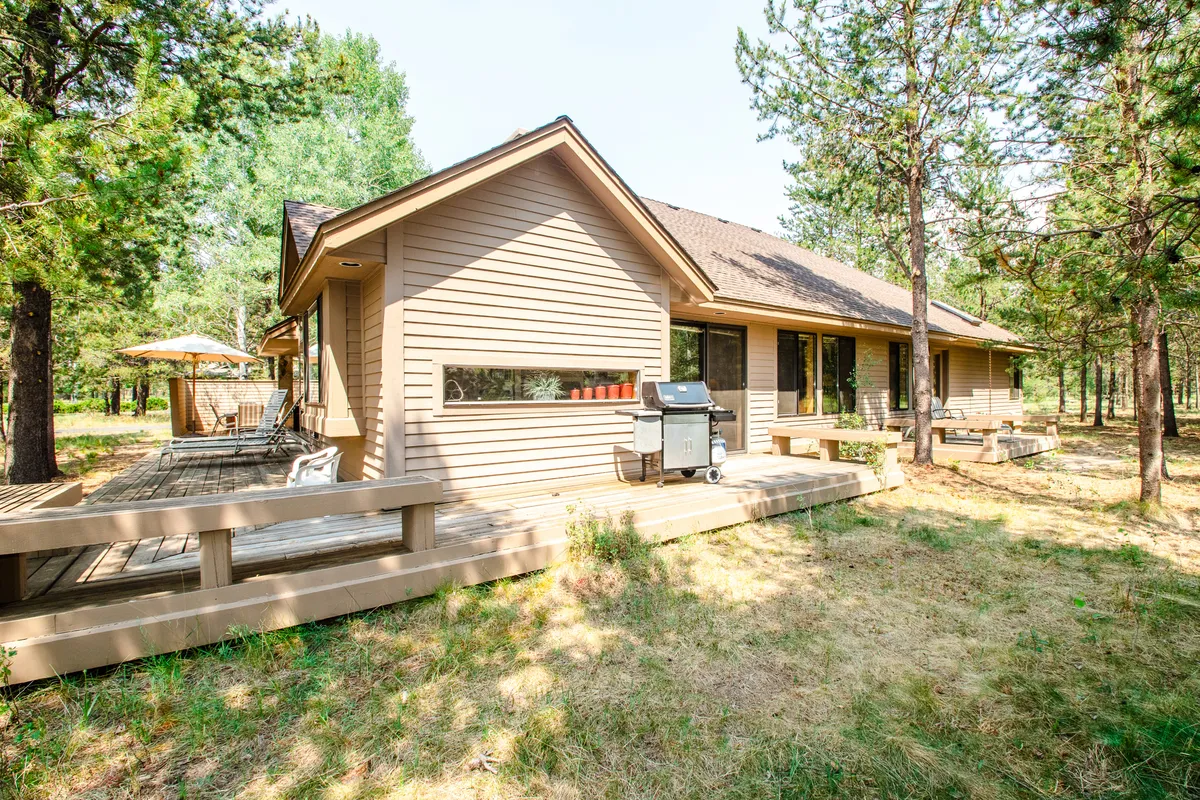 An exterior view of the home's deck with an outdoor grill and seating area. The space is set up for barbecuing and dining al fresco, with a welcoming atmosphere for sunset gatherings and family cookouts under the open sky.