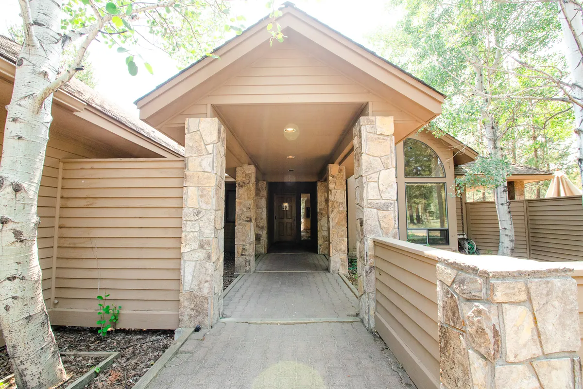 A pathway leads up to a stately, arched entrance with stone pillars, flanked by lush landscaping. The inviting entryway has a welcoming atmosphere, suggesting easy comings-and-goings for both guests and their furry companions.