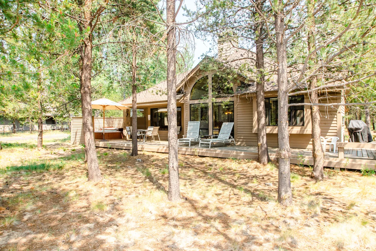 This image presents the home's exterior with an inviting deck seating area, surrounded by trees, and plenty of space for outdoor activities. The tranquil setting highlights the connection to nature and the relaxing amenities available right outside the door.