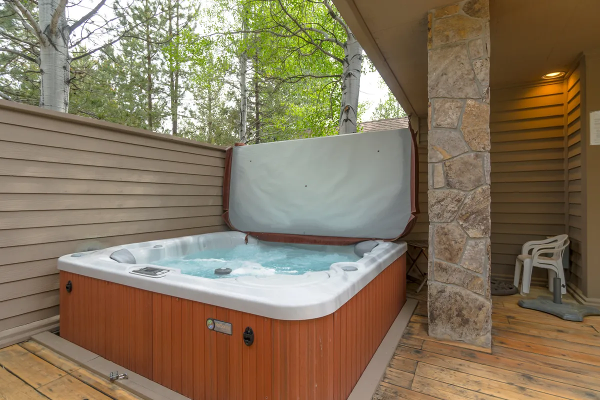 This image captures a wooden deck with a private hot tub, nestled among the trees. The area invites relaxation and socializing, perfect for unwinding after a day of exploring or gathering with friends in a peaceful outdoor setting.