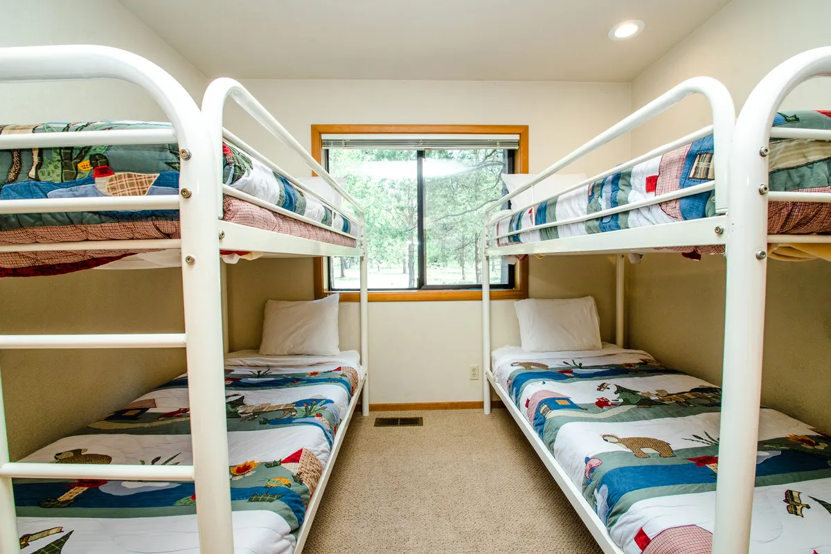 A playful bunk room with bunk beds and a window view, designed for fun and relaxation. The bedding and layout suggest a perfect space for kids or friends to share vacation memories.