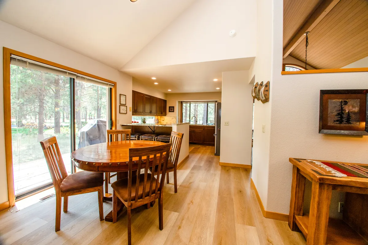 An open-concept dining area adjacent to the kitchen, featuring a spacious dining table set near large windows. The area is filled with natural light and connected to the kitchen, capturing the spirit of shared meals and communal gatherings described in the section.