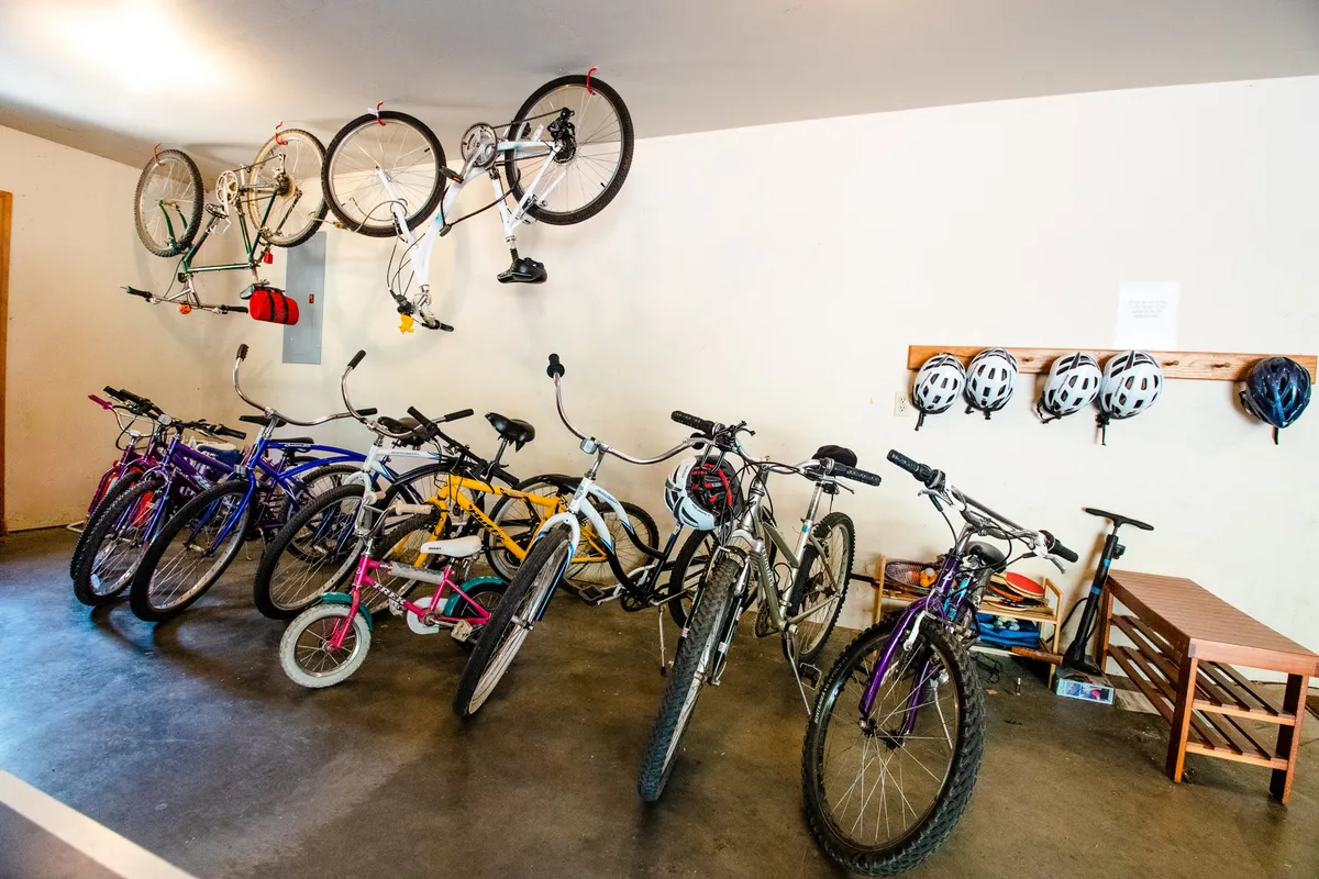 This image features a set of bicycles and helmets neatly arranged near a storage bench, suggesting readiness for outdoor adventures. The scene is active and playful, highlighting the property's provision of bikes for exploring Sunriver's trails and community spaces.